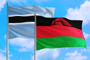 Malawi and Botswana national flag waving in the windy deep blue sky. Diplomacy and international relations concept.