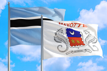 Mayotte and Botswana national flag waving in the windy deep blue sky. Diplomacy and international relations concept.