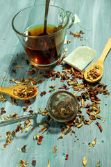 infusion leaves wooden spoons and cup of tea on table