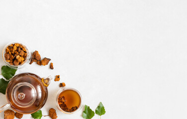 Composition with chaga tea, chaga mushroom pieces, birch leaves on a white background. Infusion...