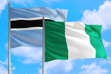 Nigeria and Botswana national flag waving in the windy deep blue sky. Diplomacy and international relations concept.