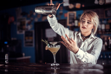 Girl barman mixes a cocktail in the saloon