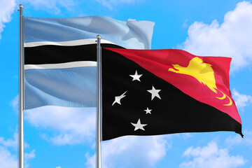Papua New Guinea and Botswana national flag waving in the windy deep blue sky. Diplomacy and international relations concept.