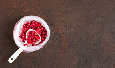 Frozen cranberry berries in a plastic bag on a brown background. Storage of frozen food. Copy space, top view.