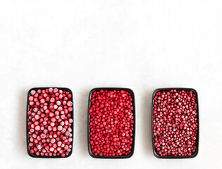 Containers with frozen berries on a white background. Cranberries, red currants and cowberries. Space for text. Top view.