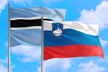 Slovenia and Botswana national flag waving in the windy deep blue sky. Diplomacy and international relations concept.