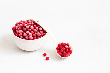 Frozen berries in a bowl on a white background. Red berries covered with frost. Frozen food. Side view. Copy space.