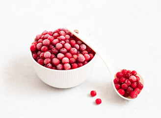 Frozen cranberries on a white background close-up. Red frozen berries in a bowl. Side view.