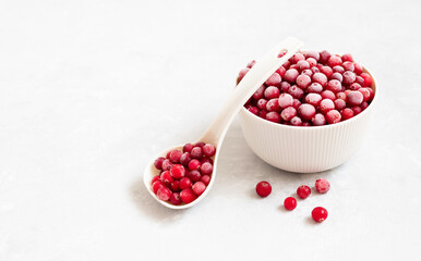 Frozen cranberry berries on a white background. Red berries with frost in a bowl. Healthy food concept. Copy space.