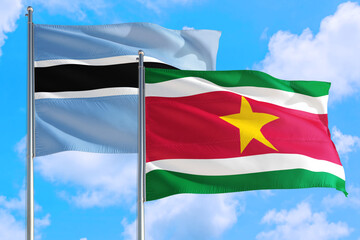 Suriname and Botswana national flag waving in the windy deep blue sky. Diplomacy and international relations concept.