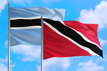 Trinidad And Tobago and Botswana national flag waving in the windy deep blue sky. Diplomacy and international relations concept.