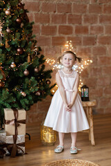 The adorable little girl in gorgeous dress standing near Christmas tree