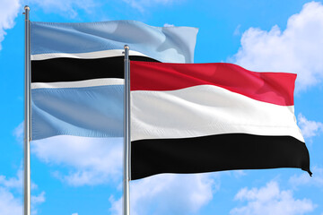 Yemen and Botswana national flag waving in the windy deep blue sky. Diplomacy and international relations concept.