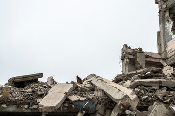 Fototapeta na wymiar A ruined building with a pile of concrete gray debris against a neutral gray sky in a hazy haze. Background