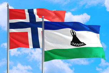 Lesotho and Bouvet Islands national flag waving in the windy deep blue sky. Diplomacy and international relations concept.