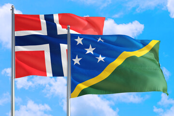 Solomon Islands and Bouvet Islands national flag waving in the windy deep blue sky. Diplomacy and...
