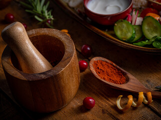 Composition with red spice in wooden spoon and mortar on table