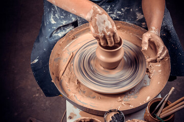 Potter female student creates a new pottery from clay on a potter's wheel. Handmade. Close-up.