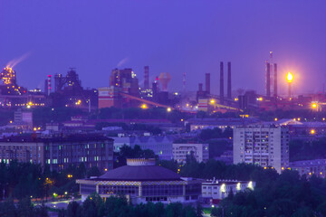 View of the evening industrial city, a large factory and the river
