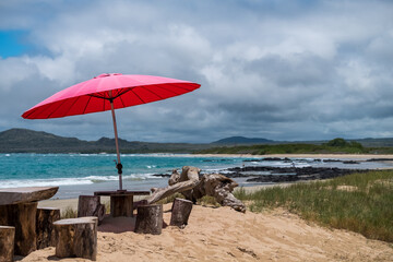 A red umbrella providing shade for people on the beach in Galapagos Islands, Ecuador