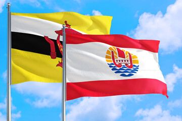 French Polynesia and Brunei national flag waving in the windy deep blue sky. Diplomacy and international relations concept.