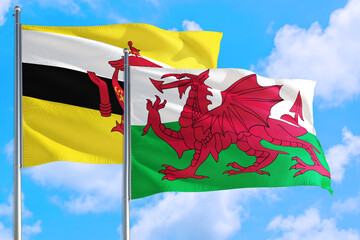 Wales and Brunei national flag waving in the windy deep blue sky. Diplomacy and international...