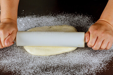 Rolling pin and white sugar paste on table.
