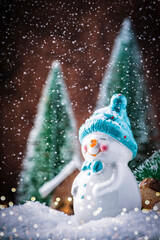 Merry Christmas and happy New Year composition with copy space. Little snowman carries Christmas tree from fairy forest to home. Winter festive background