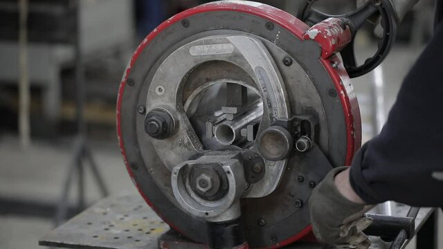 welded seam on a section of a steel pipe with the help of a grinding machine in the metal workshop