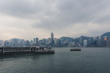 Fototapeta premium panoramic city skyline with ferries during cloudy weather