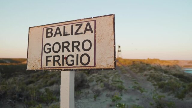 Revealing Shot Of Phrygian Cap Beacon Behind Baliza Gorro Frigio Signage In Puerto Madryn, Chubut, Argentina - slow motion