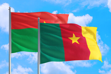 Cameroon and Burkina Faso national flag waving in the windy deep blue sky. Diplomacy and international relations concept.