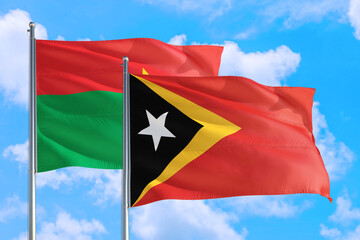 East Timor and Burkina Faso national flag waving in the windy deep blue sky. Diplomacy and international relations concept.