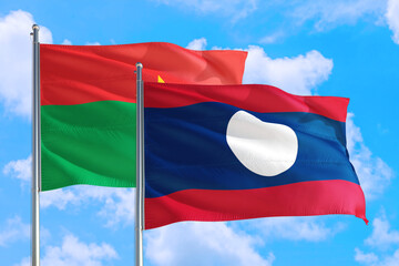 Laos and Burkina Faso national flag waving in the windy deep blue sky. Diplomacy and international relations concept.