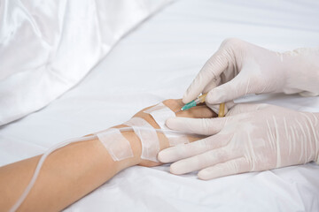Fototapeta premium Close up doctor's hand injects saline infusion needle into patient on bed 