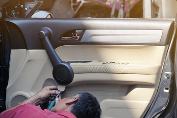 Fixing door's car engine in automobile repair garage. Mechanics in uniform are repairing car while...