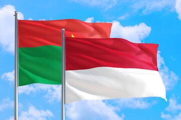 Monaco and Burkina Faso national flag waving in the windy deep blue sky. Diplomacy and international relations concept.