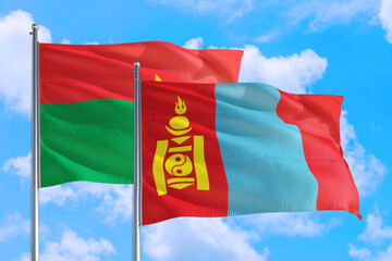 Mongolia and Burkina Faso national flag waving in the windy deep blue sky. Diplomacy and international relations concept.