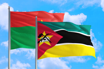 Mozambique and Burkina Faso national flag waving in the windy deep blue sky. Diplomacy and international relations concept.