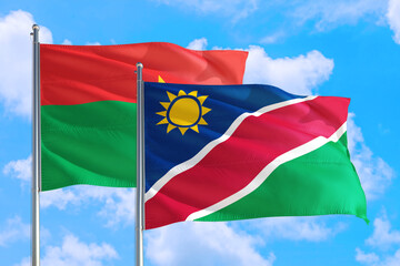 Namibia and Burkina Faso national flag waving in the windy deep blue sky. Diplomacy and international relations concept.