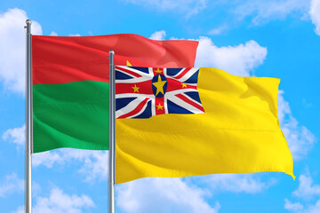 Niue and Burkina Faso national flag waving in the windy deep blue sky. Diplomacy and international relations concept.