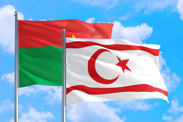 Northern Cyprus and Burkina Faso national flag waving in the windy deep blue sky. Diplomacy and international relations concept.