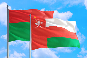 Fototapeta na wymiar Oman and Burkina Faso national flag waving in the windy deep blue sky. Diplomacy and international relations concept.