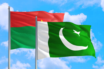 Pakistan and Burkina Faso national flag waving in the windy deep blue sky. Diplomacy and international relations concept.