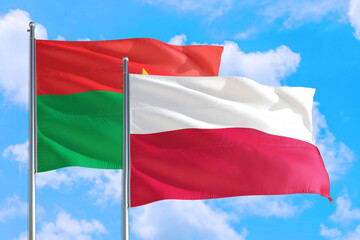 Poland and Burkina Faso national flag waving in the windy deep blue sky. Diplomacy and international relations concept.