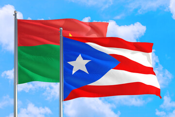 Puerto Rico and Burkina Faso national flag waving in the windy deep blue sky. Diplomacy and international relations concept.