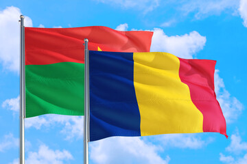 Romania and Burkina Faso national flag waving in the windy deep blue sky. Diplomacy and international relations concept.