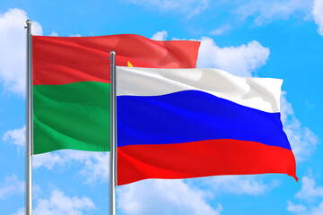 Fototapeta na wymiar Russia and Burkina Faso national flag waving in the windy deep blue sky. Diplomacy and international relations concept.