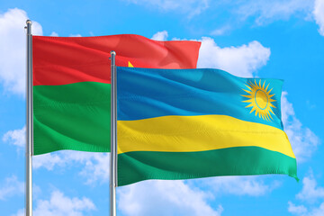 Rwanda and Burkina Faso national flag waving in the windy deep blue sky. Diplomacy and international relations concept.