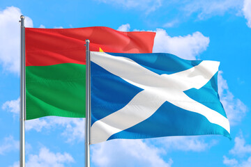 Scotland and Burkina Faso national flag waving in the windy deep blue sky. Diplomacy and international relations concept.